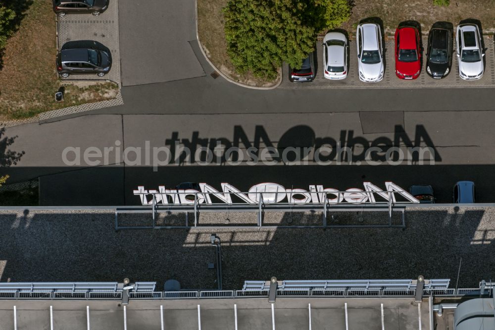 Aerial photograph Leipzig - Part of the roof of the building of the shopping center Paunsdorf Center with the shadow of the letters Mediamarkt in the district Paunsdorf in Leipzig in the state Saxony, Germany