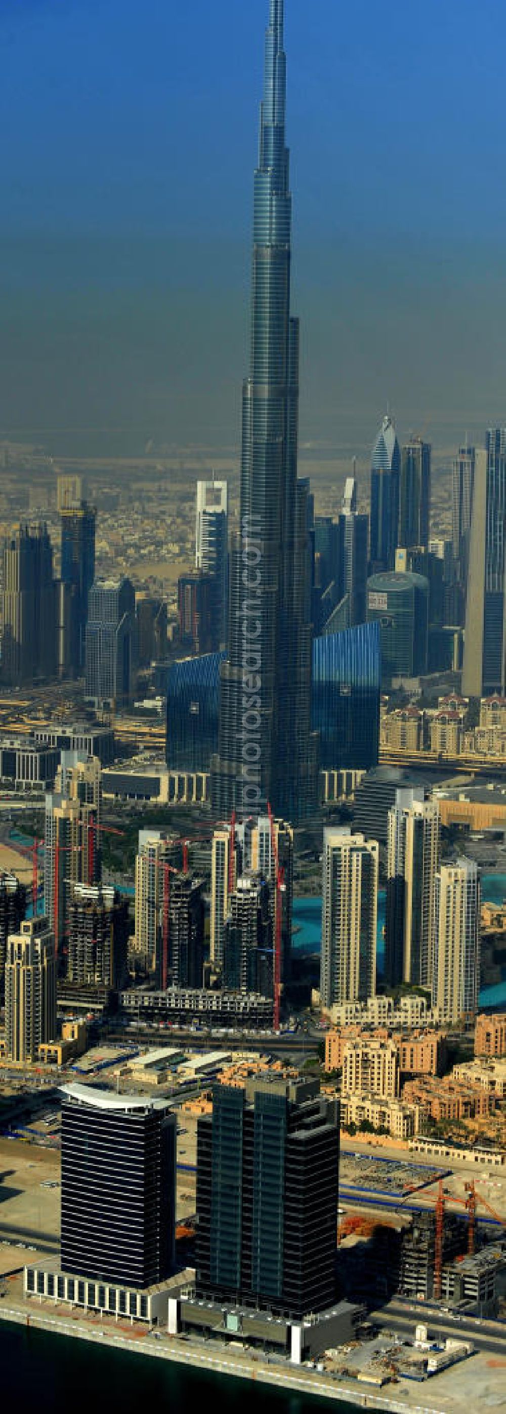 DUBAI / DUBAYY from the bird's eye view: Blick auf das Burj Khalifa in der Skyline von Dubai, dem derzeit höchsten Gebäude der Welt. Das Hochhaus wurde von der Projektgesellschaft Emaar Properties nach Plänen des Architekten Adrian Smith vom amerikanischen Architekturbüro Skidmore, Owings and Merrill gebaut. Das Hochhaus ist Mittelpunkt von Downtown Dubai, eines neuen Stadtentwicklungsgebietes. In den unteren 37 der allgemein nutzbaren 163 Etagen ist das weltweit erste Armani-Hotel eingezogen. Einige tausend Tonnen Stahl in den oberen Geschossen sind Recycling-Stahl aus dem abgerissenen Palast der Republik in Berlin. Die Firma Bauer Spezialtiefbau als Subunternehmer bei der Fundamentlegung. Der verarbeitungsfertige flüssige Beton wurde mit Hochleistungsbetonpumpen der Firma Putzmeister auf die jeweilige Arbeitshöhe transportiert. Skyscraper Burj Khalifa, currently the tallest building in the world.