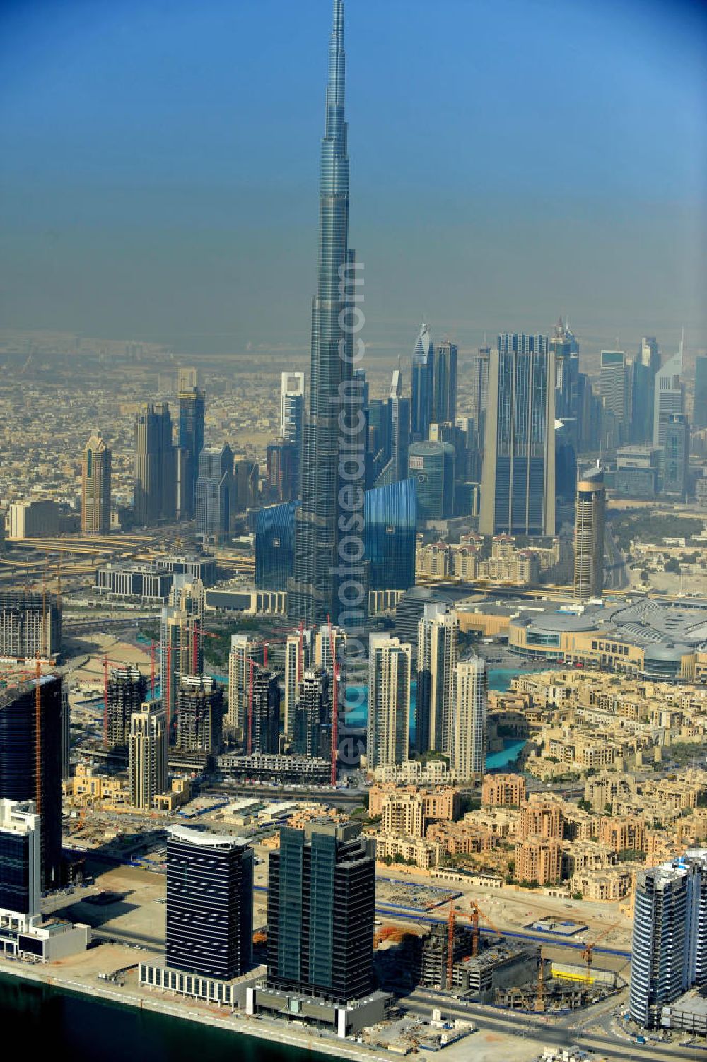 Aerial image DUBAI / DUBAYY - Blick auf das Burj Khalifa in der Skyline von Dubai, dem derzeit höchsten Gebäude der Welt. Das Hochhaus wurde von der Projektgesellschaft Emaar Properties nach Plänen des Architekten Adrian Smith vom amerikanischen Architekturbüro Skidmore, Owings and Merrill gebaut. Das Hochhaus ist Mittelpunkt von Downtown Dubai, eines neuen Stadtentwicklungsgebietes. In den unteren 37 der allgemein nutzbaren 163 Etagen ist das weltweit erste Armani-Hotel eingezogen. Einige tausend Tonnen Stahl in den oberen Geschossen sind Recycling-Stahl aus dem abgerissenen Palast der Republik in Berlin. Die Firma Bauer Spezialtiefbau als Subunternehmer bei der Fundamentlegung. Der verarbeitungsfertige flüssige Beton wurde mit Hochleistungsbetonpumpen der Firma Putzmeister auf die jeweilige Arbeitshöhe transportiert. Skyscraper Burj Khalifa, currently the tallest building in the world.