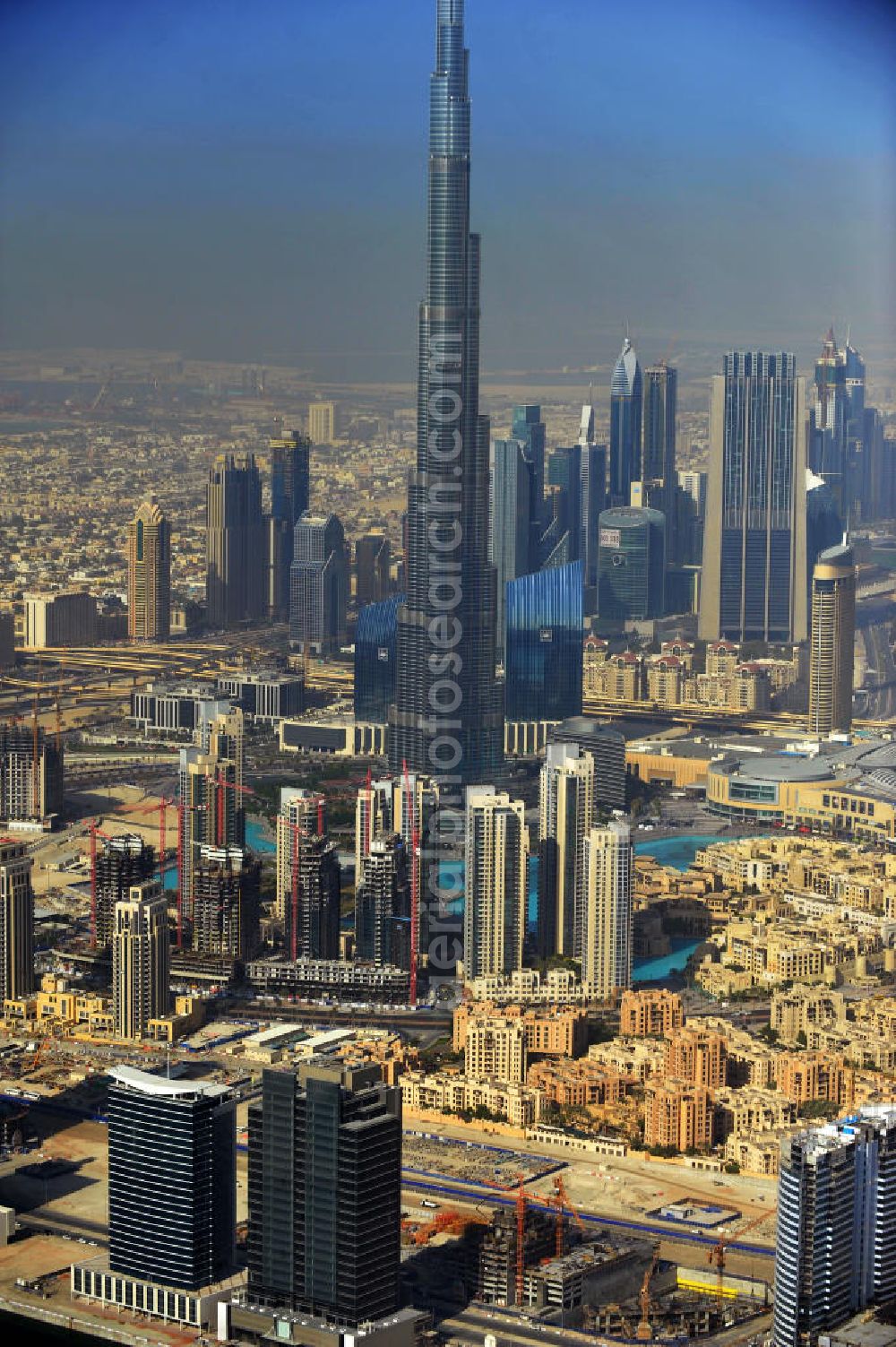 Aerial photograph DUBAI / DUBAYY - Blick auf das Burj Khalifa in der Skyline von Dubai, dem derzeit höchsten Gebäude der Welt. Das Hochhaus wurde von der Projektgesellschaft Emaar Properties nach Plänen des Architekten Adrian Smith vom amerikanischen Architekturbüro Skidmore, Owings and Merrill gebaut. Das Hochhaus ist Mittelpunkt von Downtown Dubai, eines neuen Stadtentwicklungsgebietes. In den unteren 37 der allgemein nutzbaren 163 Etagen ist das weltweit erste Armani-Hotel eingezogen. Einige tausend Tonnen Stahl in den oberen Geschossen sind Recycling-Stahl aus dem abgerissenen Palast der Republik in Berlin. Die Firma Bauer Spezialtiefbau als Subunternehmer bei der Fundamentlegung. Der verarbeitungsfertige flüssige Beton wurde mit Hochleistungsbetonpumpen der Firma Putzmeister auf die jeweilige Arbeitshöhe transportiert. Skyscraper Burj Khalifa, currently the tallest building in the world.