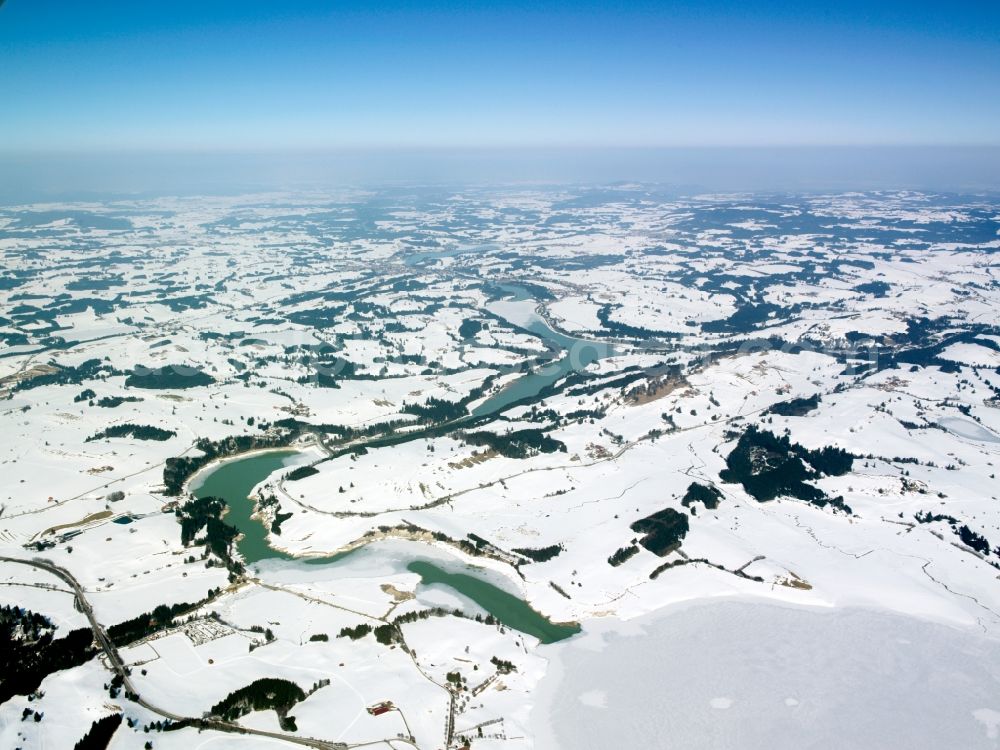 Roßhaupten from above - The river Lech near Roßhaupten in the county district of Ostallgäu in Swabia in the state of Bavaria. The river runs through the winter landscape. Hills and fields are covered by snow. In the background lies Roßhaupten and the lake Forggensee
