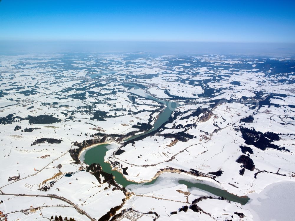 Roßhaupten from the bird's eye view: The river Lech near Roßhaupten in the county district of Ostallgäu in Swabia in the state of Bavaria. The river runs through the winter landscape. Hills and fields are covered by snow. In the background lies Roßhaupten and the lake Forggensee