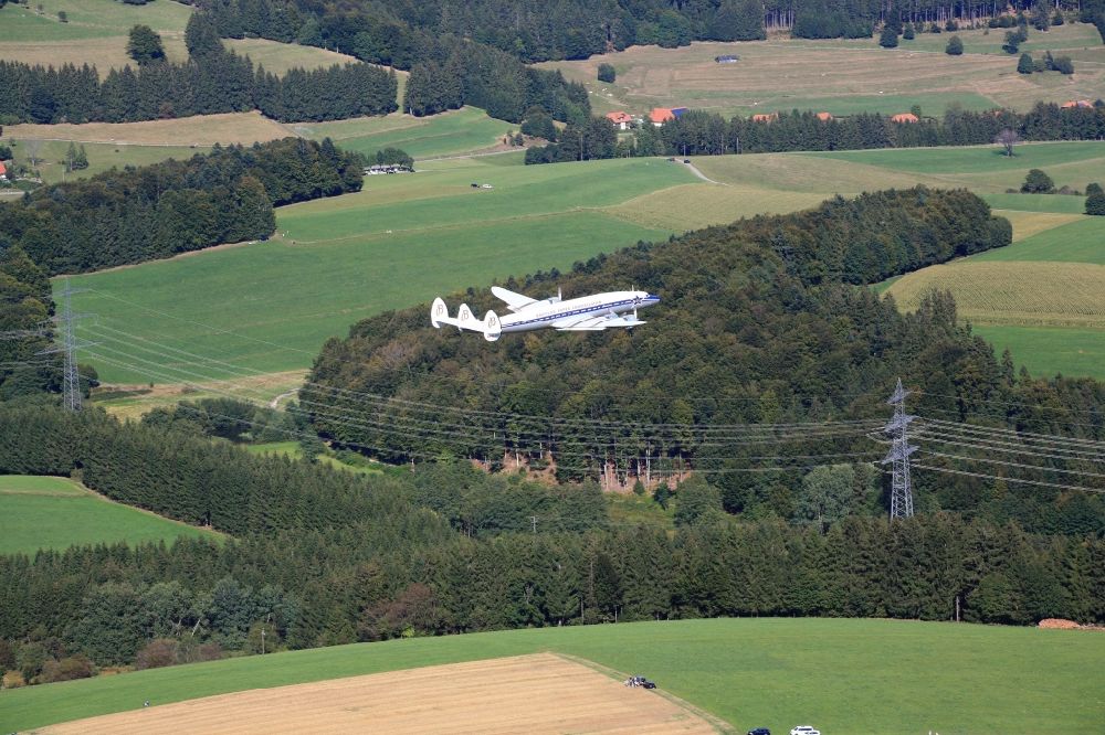 Rickenbach from the bird's eye view: The historic airliner Lockheed Super Constellation is flying over the landscape of the Hotzenwald to approach the gliderfield of the air sports community Hotzenwald in Rickenbach in the state of Baden- Wuerttemberg at the international air show