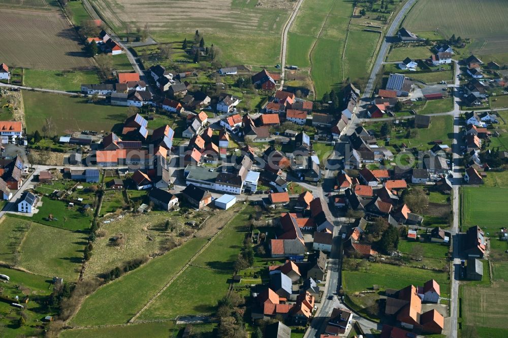 Hilwartshausen from above - Agricultural land and field boundaries surround the settlement area of the village in Hilwartshausen in the state Lower Saxony, Germany