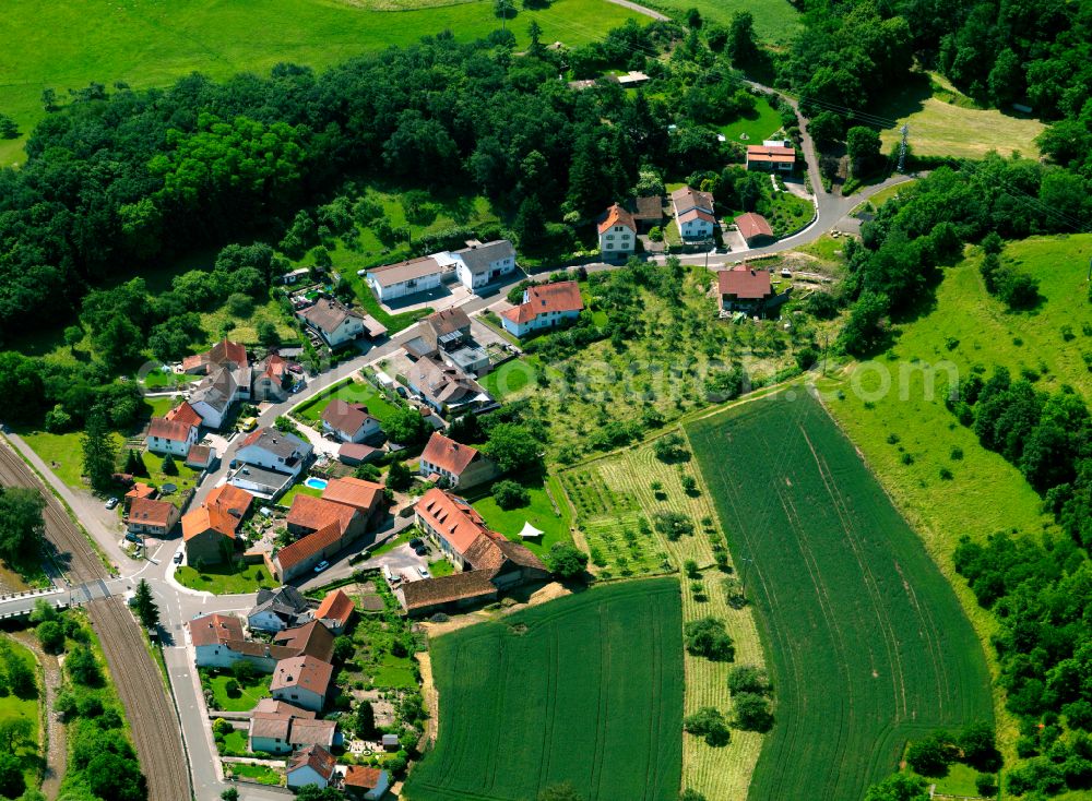 Mannweiler from above - Agricultural land and field boundaries surround the settlement area of the village in Mannweiler in the state Rhineland-Palatinate, Germany