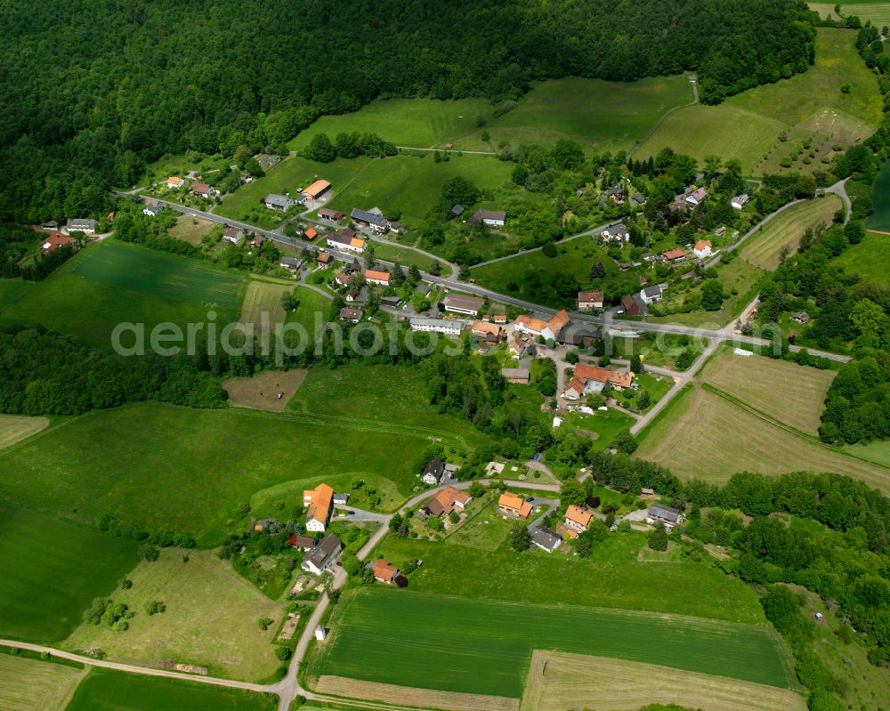 Schadges from the bird's eye view: Agricultural land and field boundaries surround the settlement area of the village in Schadges in the state Hesse, Germany