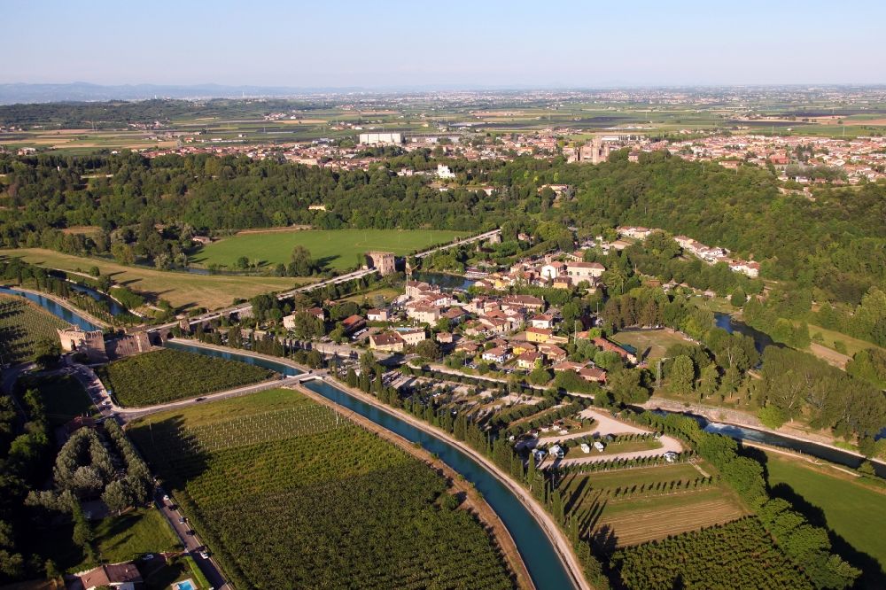 Valeggio sul Mincio from the bird's eye view: Village on the river bank areas of Mincio in the district Borghetto in Valeggio sul Mincio in Veneto, Italy. The picturesque district of Borghetto is one of the most beautiful villages in Italy. Across the river leads the historic bridge Ponte Visconteo. Borghetto used to be a fishing village. It has become a popular tourist destination. There are various restaurants and bars. Noteworthy are the watermills, some of which are still in operation