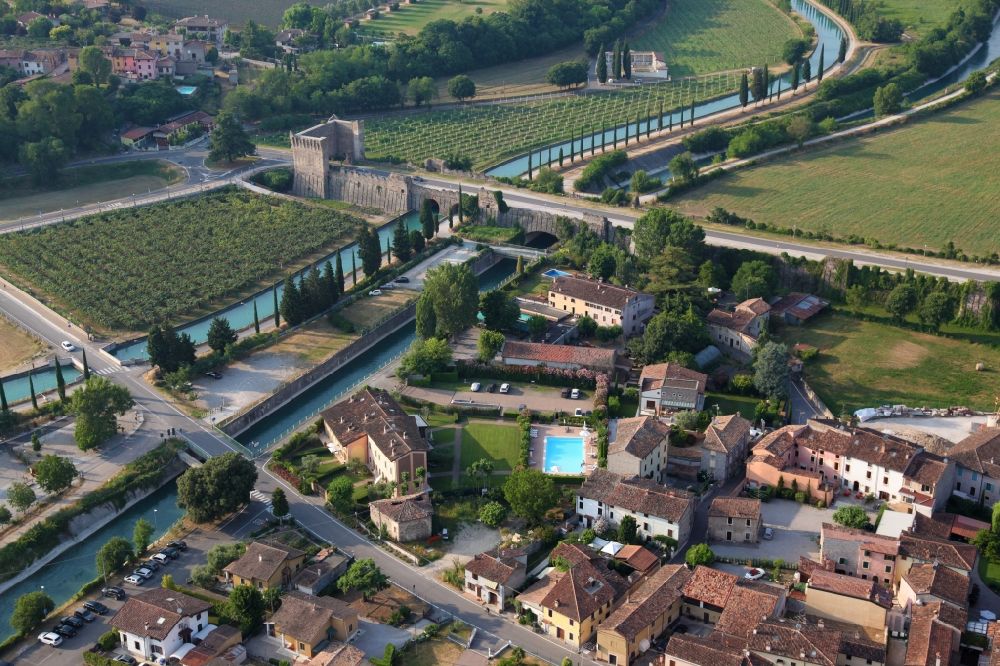 Aerial photograph Valeggio sul Mincio - Village on the river bank areas of Mincio in the district Borghetto in Valeggio sul Mincio in Veneto, Italy. The picturesque district of Borghetto is one of the most beautiful villages in Italy. Across the river leads the historic bridge Ponte Visconteo. Borghetto used to be a fishing village. It has become a popular tourist destination. There are various restaurants and bars. Noteworthy are the watermills, some of which are still in operation