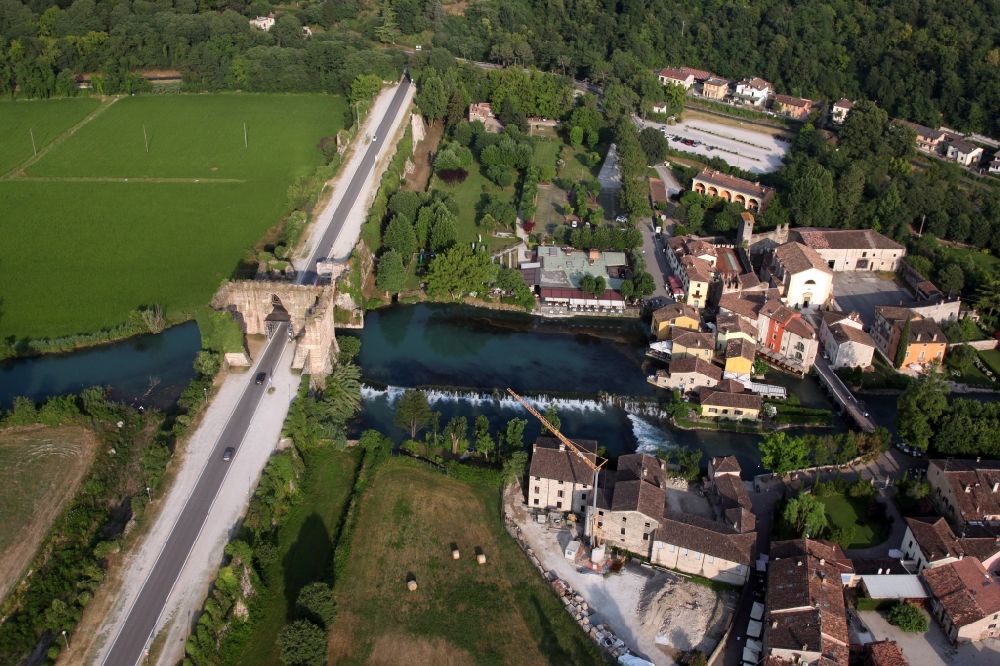 Valeggio sul Mincio from above - Village on the river bank areas of Mincio in the district Borghetto in Valeggio sul Mincio in Veneto, Italy. The picturesque district of Borghetto is one of the most beautiful villages in Italy. Across the river leads the historic bridge Ponte Visconteo. Borghetto used to be a fishing village. It has become a popular tourist destination. There are various restaurants and bars. Noteworthy are the watermills, some of which are still in operation