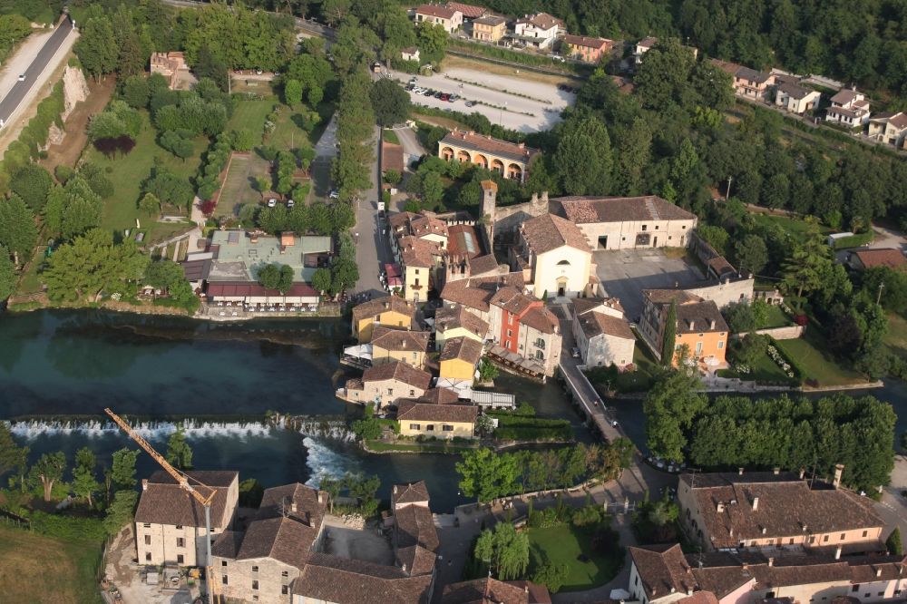 Aerial photograph Valeggio sul Mincio - Village on the river bank areas of Mincio in the district Borghetto in Valeggio sul Mincio in Veneto, Italy. The picturesque district of Borghetto is one of the most beautiful villages in Italy. Borghetto used to be a fishing village. It has become a popular tourist destination. There are various restaurants and bars. Noteworthy are the watermills, some of which are still in operation