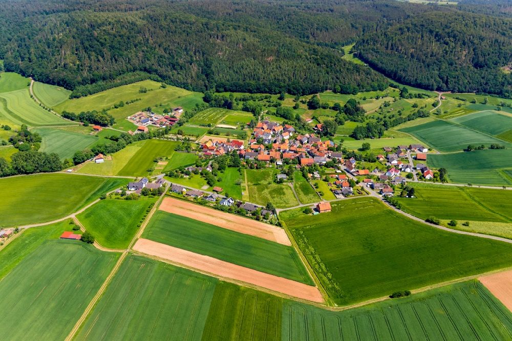 Königshagen from above - Agricultural land and field borders surround the settlement area of the village in Koenigshagen in the state Hesse, Germany