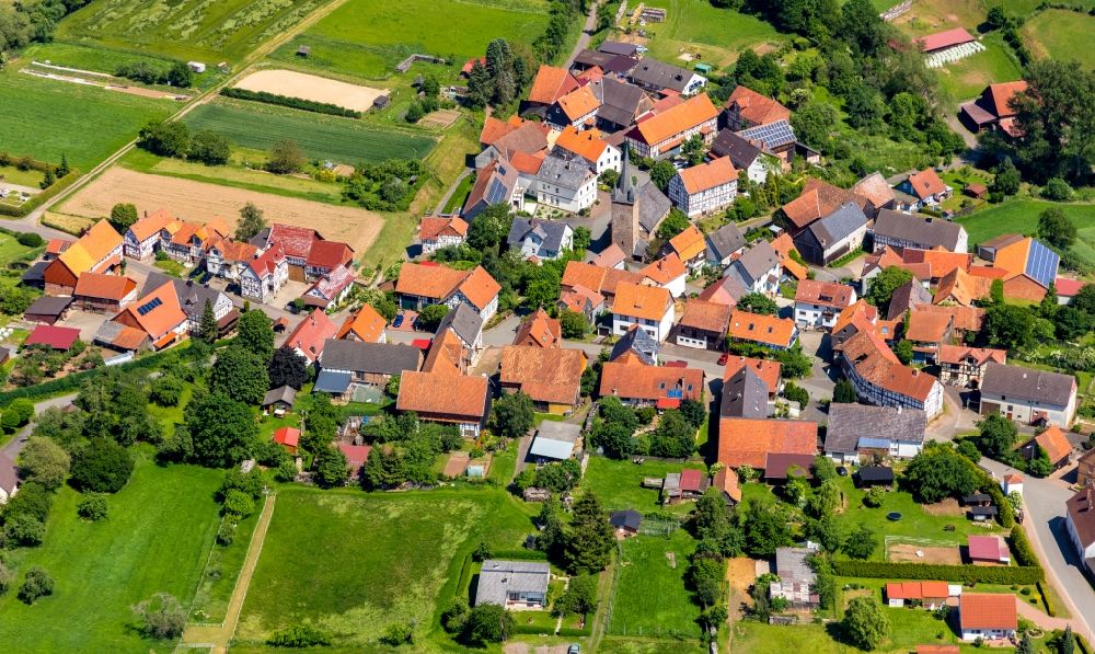 Königshagen from the bird's eye view: Agricultural land and field borders surround the settlement area of the village in Koenigshagen in the state Hesse, Germany