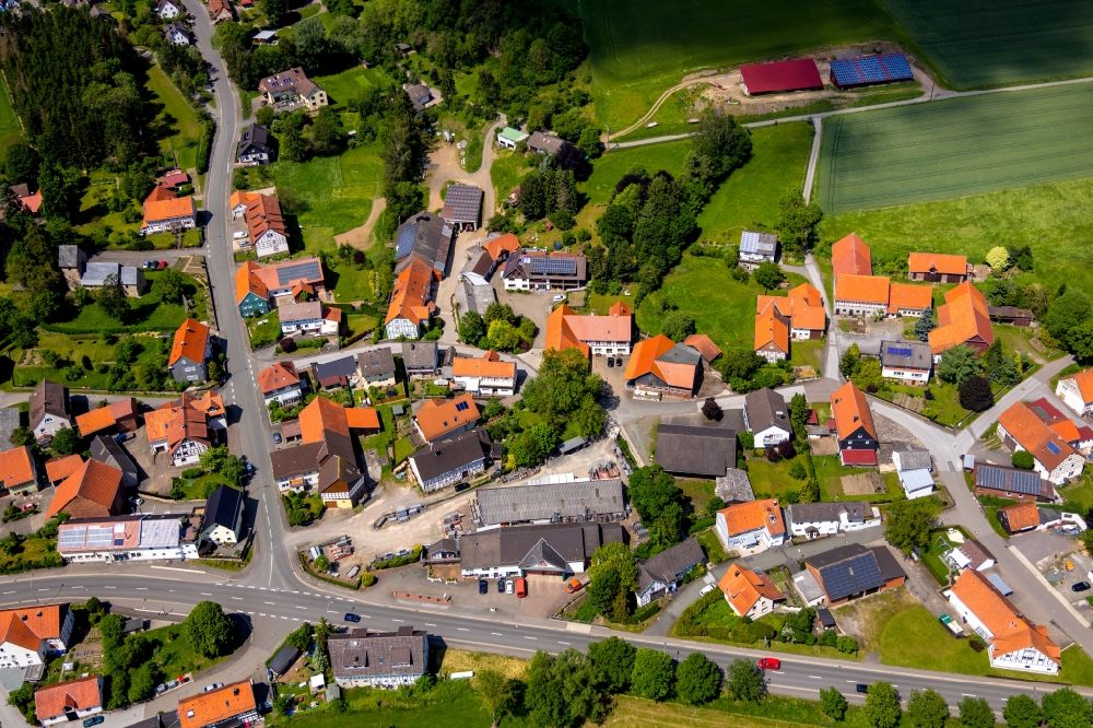 Rhena from above - Agricultural land and field borders surround the settlement area of the village in Rhena in the state Hesse, Germany