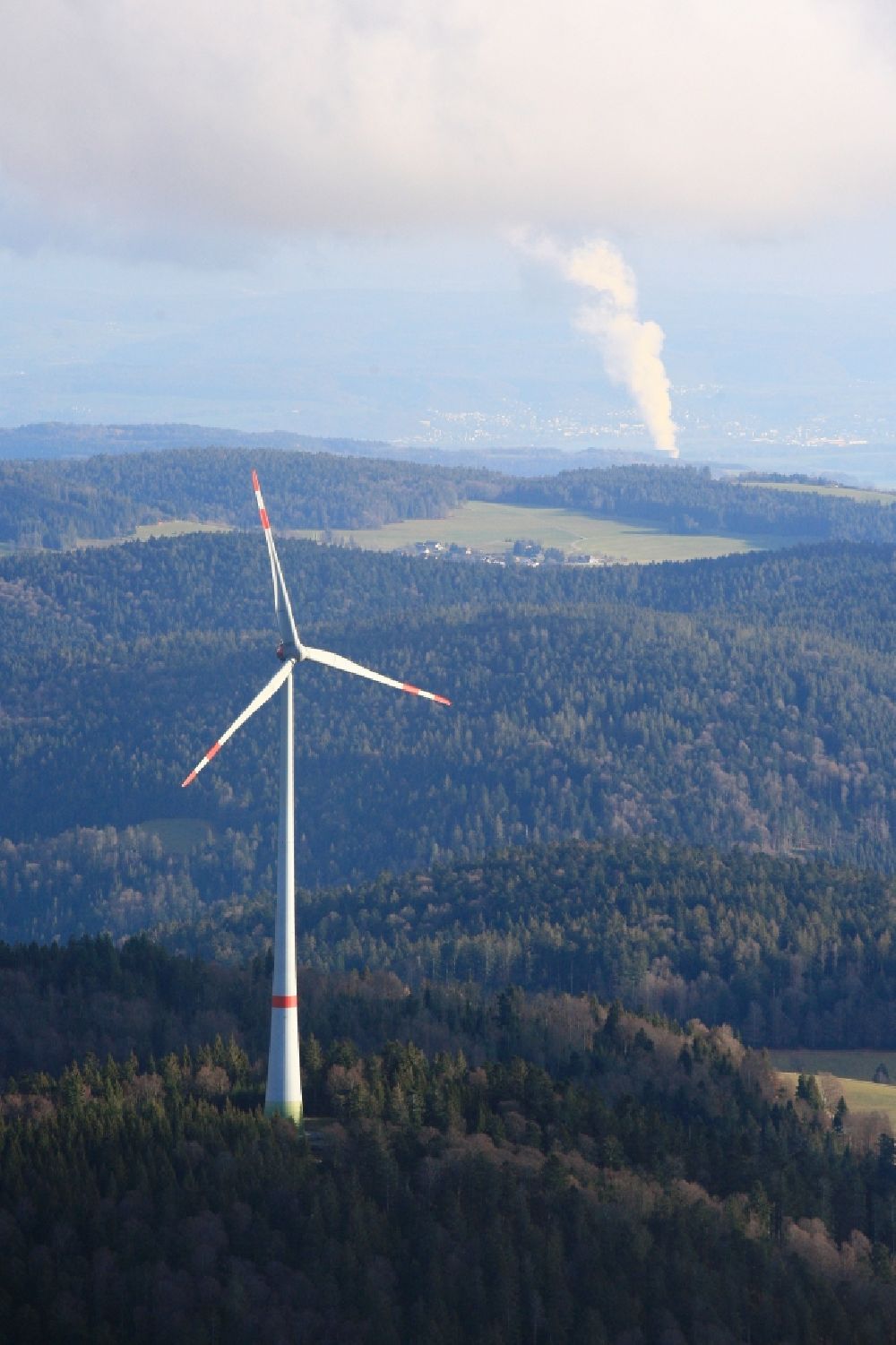 Schopfheim from the bird's eye view: Wind turbines of the wind farm Rohrenkopf in the Black Forest in Gersbach in the state Baden-Wurttemberg, Germany. In the background the steam column of swiss nuclear power plant Leibstadt KKL. Symbolic image for the controversial debate of nuclear power versus renewable power