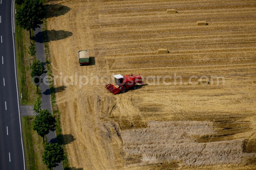 Fuldabrück from the bird's eye view: Harvest use of heavy agricultural machinery - combine harvesters and harvesting vehicles on agricultural fields in Fuldabrueck in the state Hesse, Germany