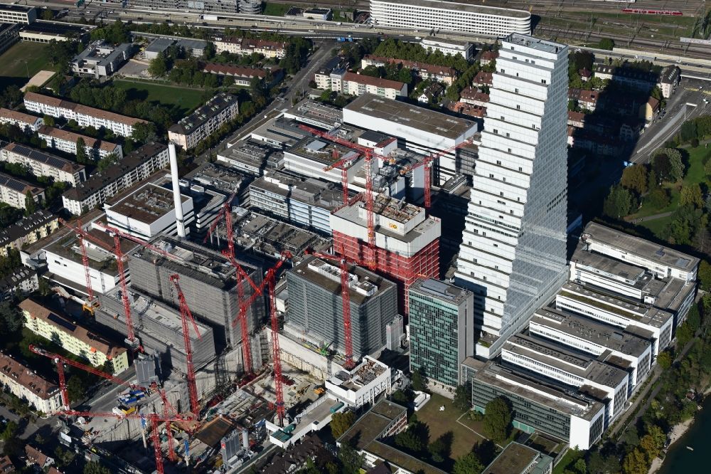 Basel from the bird's eye view: Extension construction sites on the premises of the pharmaceutical company Roche with the cityscape-defining high-rise building in Basel in Switzerland. Construction works for the second tower are visible