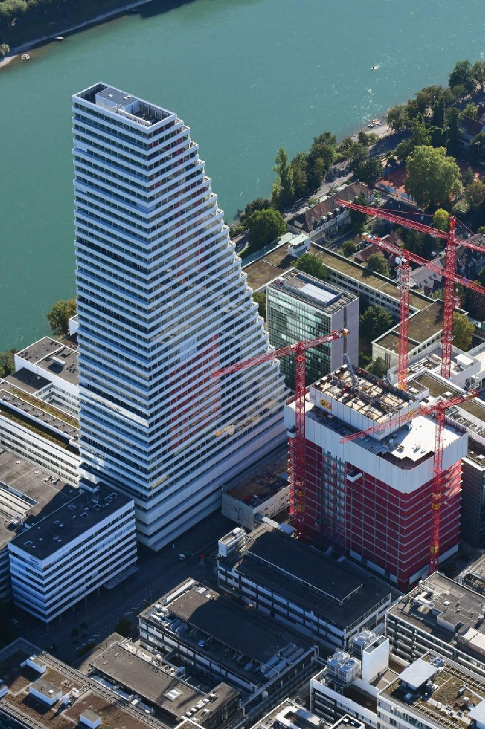 Basel from above - Extension construction sites on the premises of the pharmaceutical company Roche with the cityscape-defining high-rise building in Basel in Switzerland. Construction works for the second tower are visible