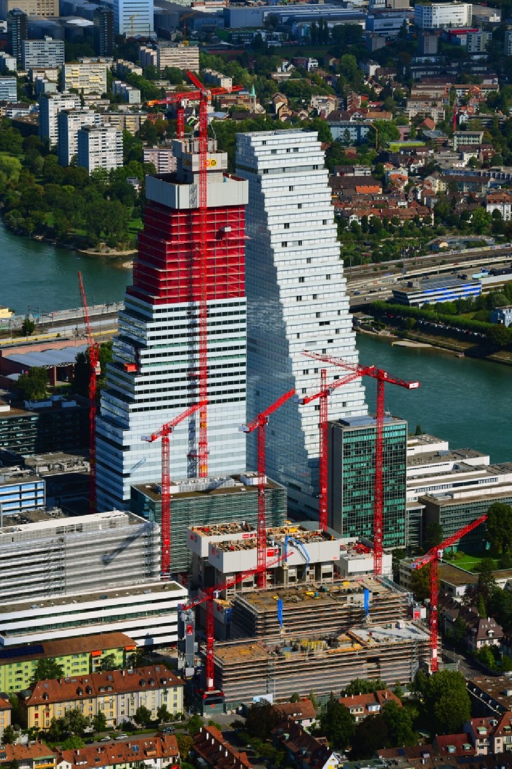Basel from above - Extension construction sites on the premises of the pharmaceutical company Roche with the cityscape-defining high-rise building in Basel in Switzerland. Construction works for the second tower are visible