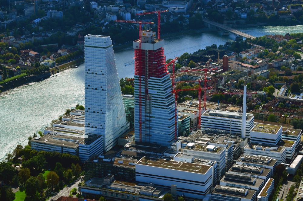Basel from the bird's eye view: Extension construction sites on the premises of the pharmaceutical company Roche with the cityscape-defining high-rise building in Basel in Switzerland. Construction works for the second tower are visible