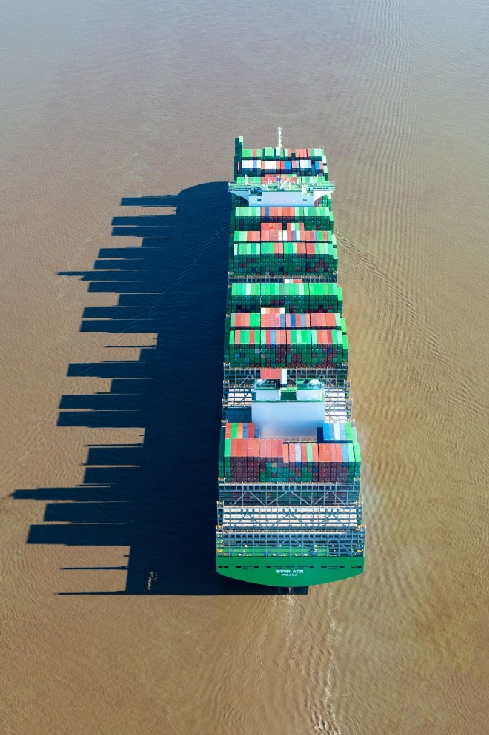 Aerial photograph Stade - Sailing container ship Ever Ace at the Elbe river during sunset in Hamburg, Germany