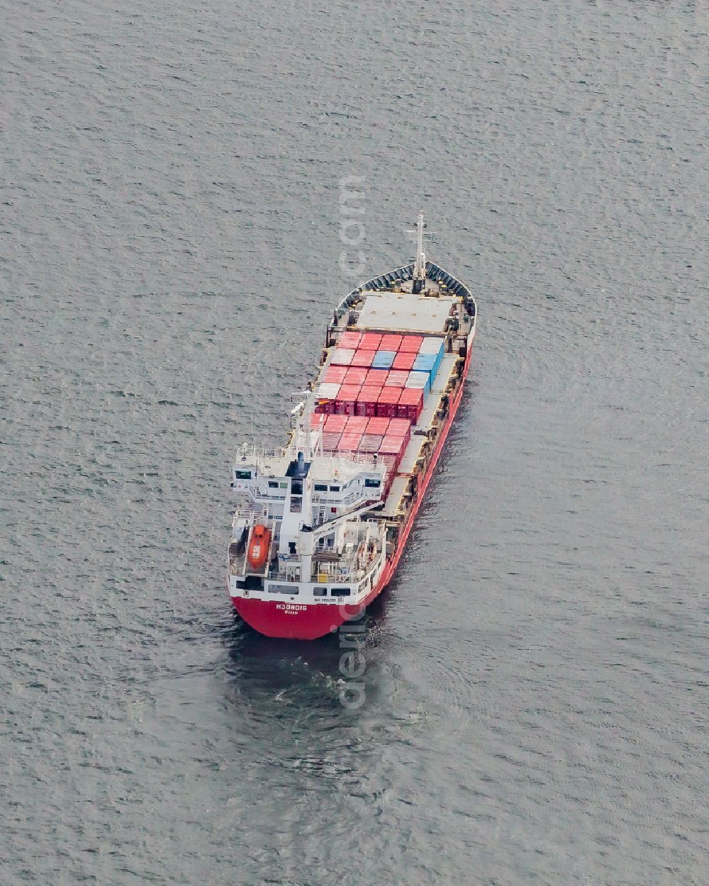 Kiel from above - Travel of a container ship on the Kiel Fjord in front of the Holtenauer Reede in Kiel in the state Schleswig-Holstein, Germany. The cargo ship HJOeRDIS ( IMO 9126235 ) of the Finnish shipping company Langh Ship Oy Ab in waiting position in Holtenau