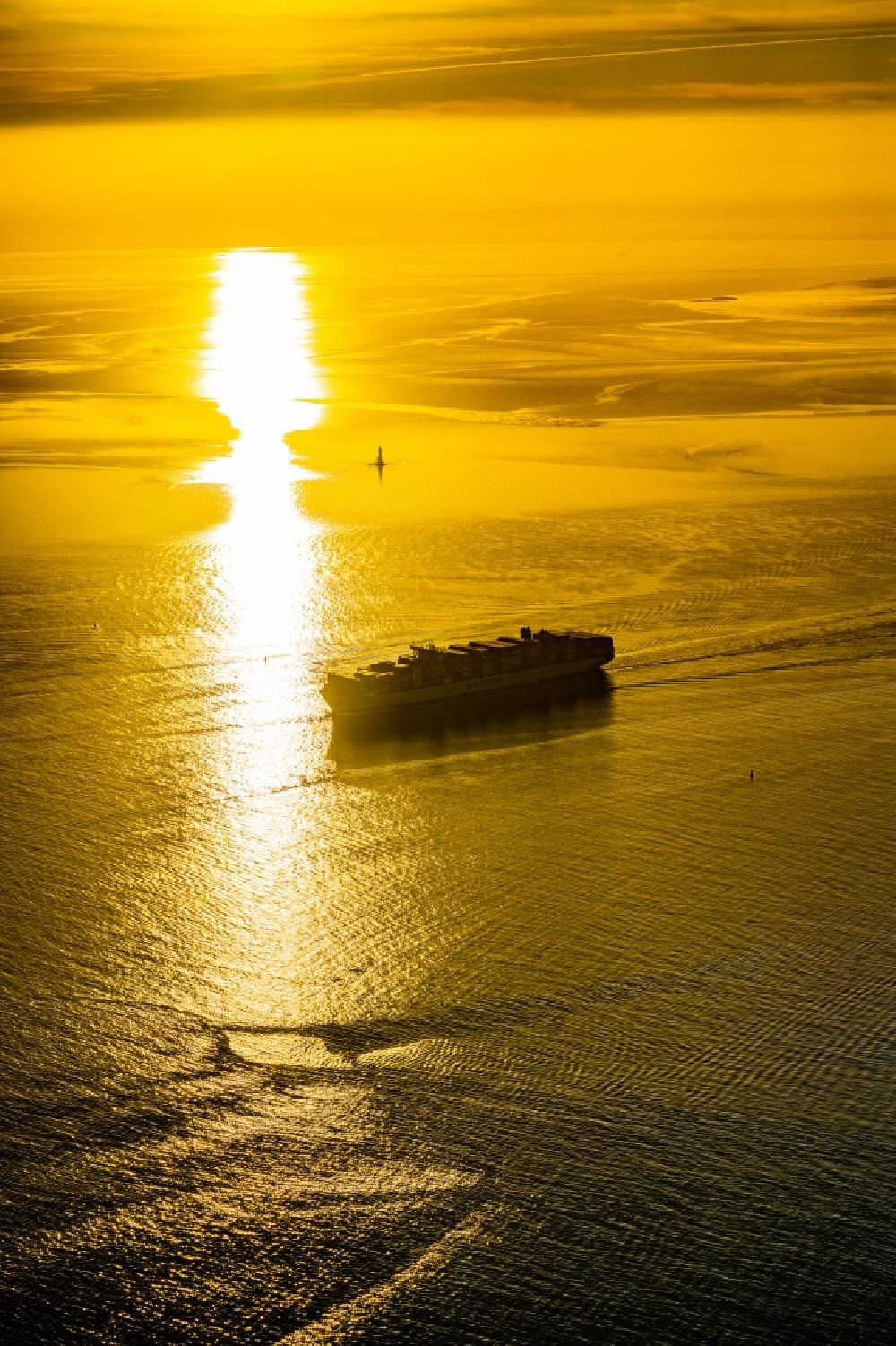 Butjadingen from the bird's eye view: Moving container ship Maribor Maersk in the sunset in the Weser estuary in Butjadingen in the state Lower Saxony, Germany