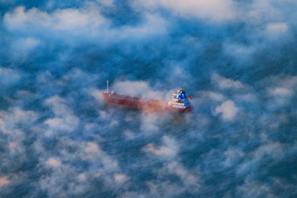 Aerial photograph Hetlingen - Sailing container ship on the river Elbe covered in fog in Hetlingen in the state Schleswig-Holstein, Germany