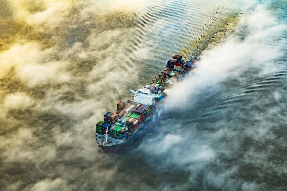 Drochtersen from the bird's eye view: Sailing container ship in fog Layer on Elbe river course in Drochtersen in the state Lower Saxony, Germany
