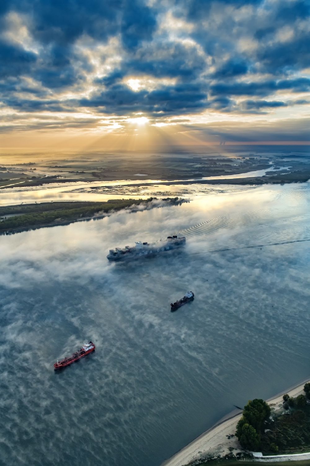 Drochtersen from the bird's eye view: Sailing container ship in fog Layer on Elbe river course in Drochtersen in the state Lower Saxony, Germany