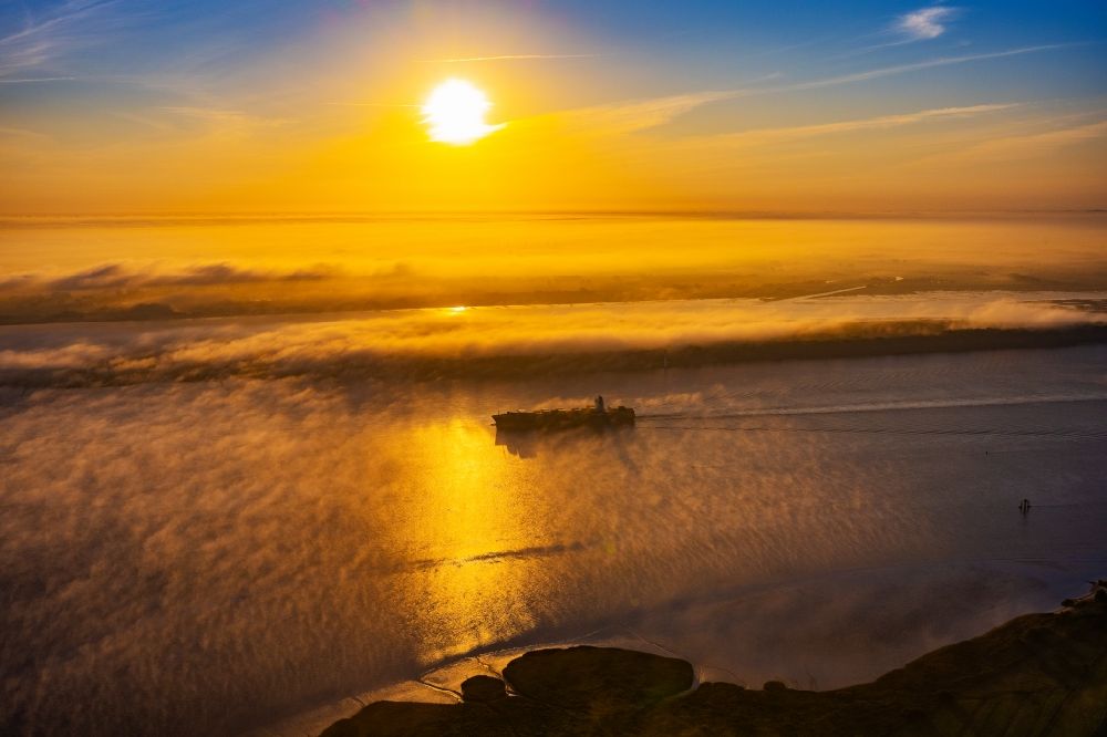 Aerial photograph Kollmar - Voyage of a container ship of the SEASPAN DALIAN IMO: 9227027 in a layer of fog at sunrise on the course of the Elbe river in Kolmar in the state Schleswig-Holstein, Germany