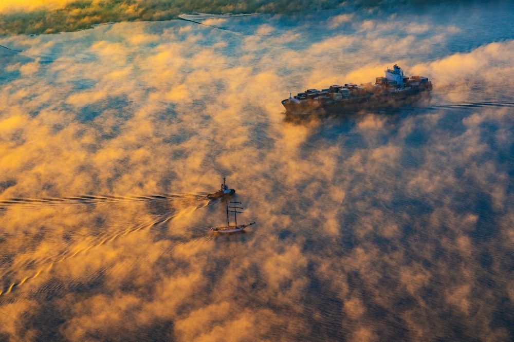 Aerial photograph Kollmar - Voyage of a container ship of the SEASPAN DALIAN IMO: 9227027 in a layer of fog at sunrise on the course of the Elbe river in Kolmar in the state Schleswig-Holstein, Germany