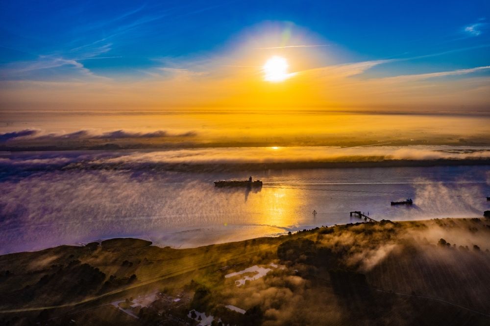 Aerial image Kollmar - Voyage of a container ship of the SEASPAN DALIAN IMO: 9227027 in a layer of fog at sunrise on the course of the Elbe river in Kolmar in the state Schleswig-Holstein, Germany