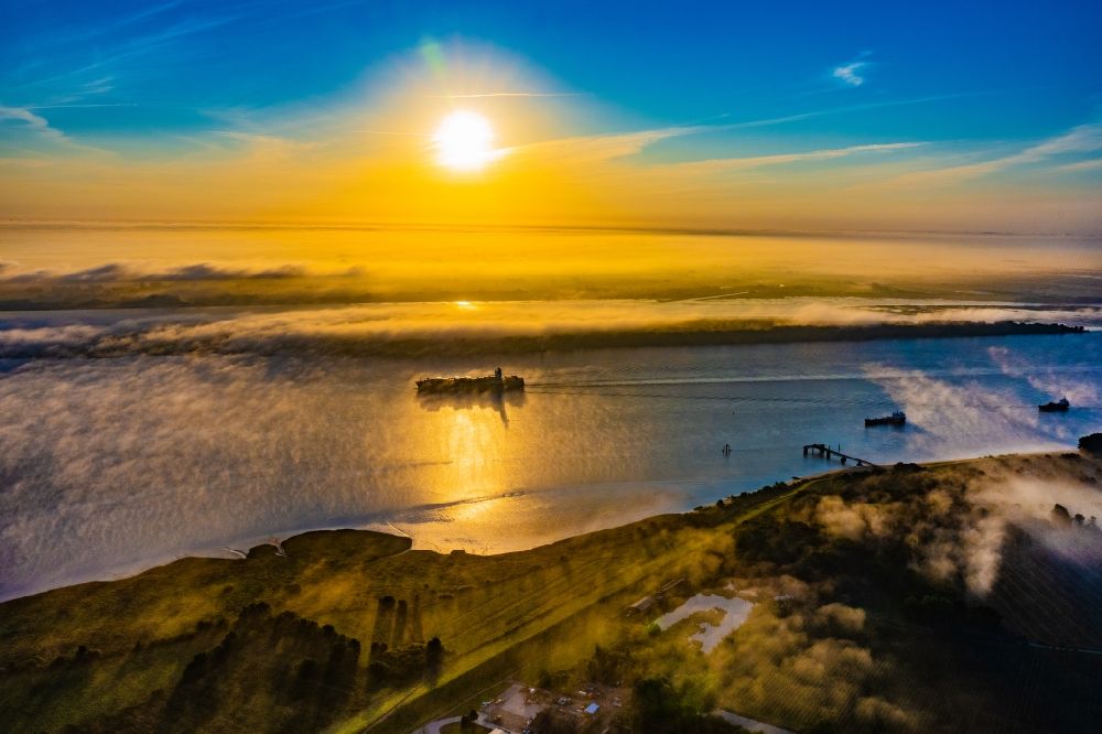 Kollmar from above - Voyage of a container ship of the SEASPAN DALIAN IMO: 9227027 in a layer of fog at sunrise on the course of the Elbe river in Kolmar in the state Schleswig-Holstein, Germany
