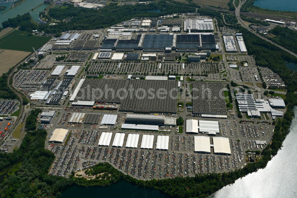 Wörth am Rhein from the bird's eye view: Buildings and production halls on the vehicle construction site and parking spaces for new vehicles in Woerth am Rhein in the state Rhineland-Palatinate, Germany