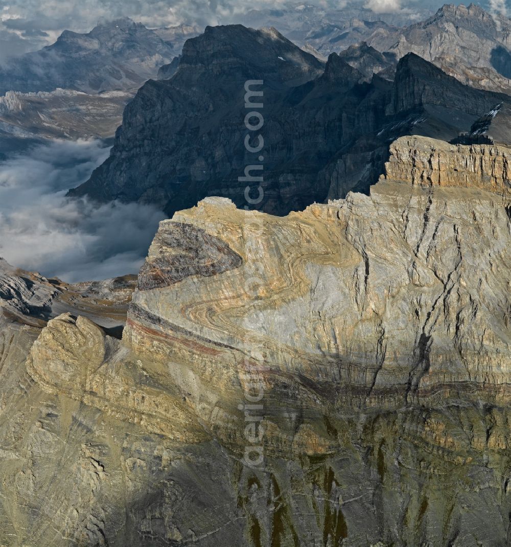 Lavey-Morcles from the bird's eye view: Rock and mountain landscape Dent de Morcles in Lavey-Morcles in Vaud, Switzerland. The huge fold in the flank of the 2969 m high Dent de Morcles is an impressive witness of the collision between Africa and Europe. The layers, originally deposited on the sea floor in a horizontal position, were compressed and shifted. The darker parts developed during Tertiary period. They are younger than the greyish and yellowish limestone of the Cretaceous period