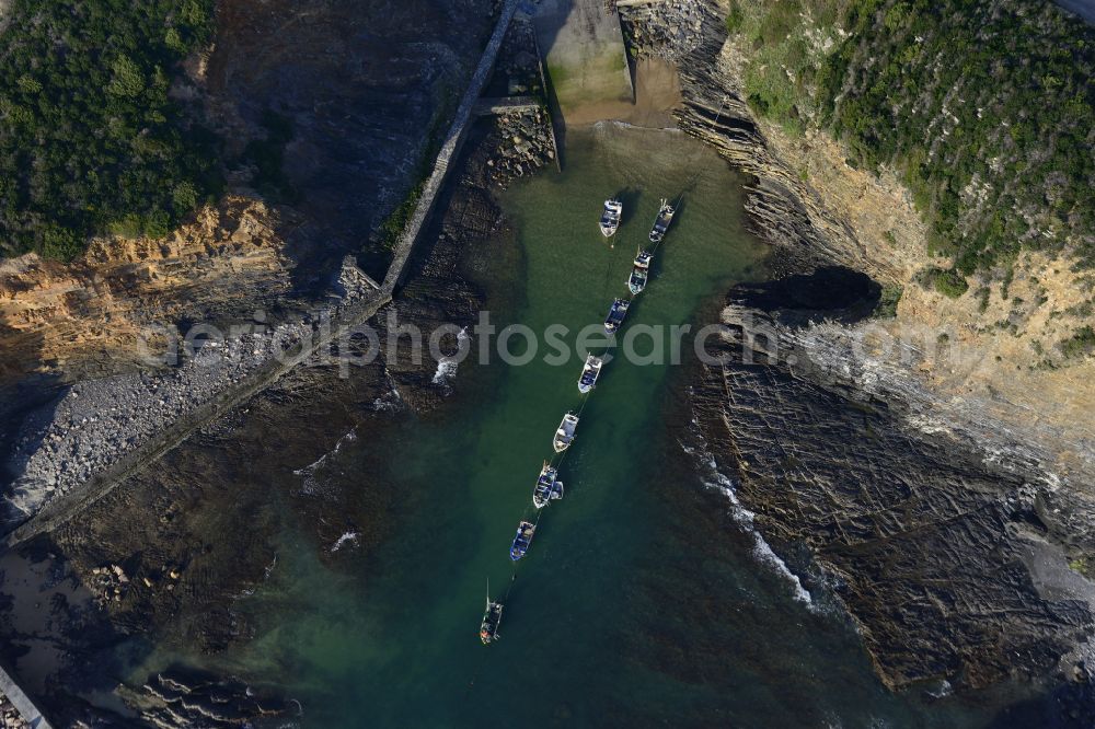Aerial photograph Porto das Barcas - Water surface with anchored fishing boats at a bay along the sea coast at the Atlantic Ocean in Porto das Barcas in Beja, Portugal