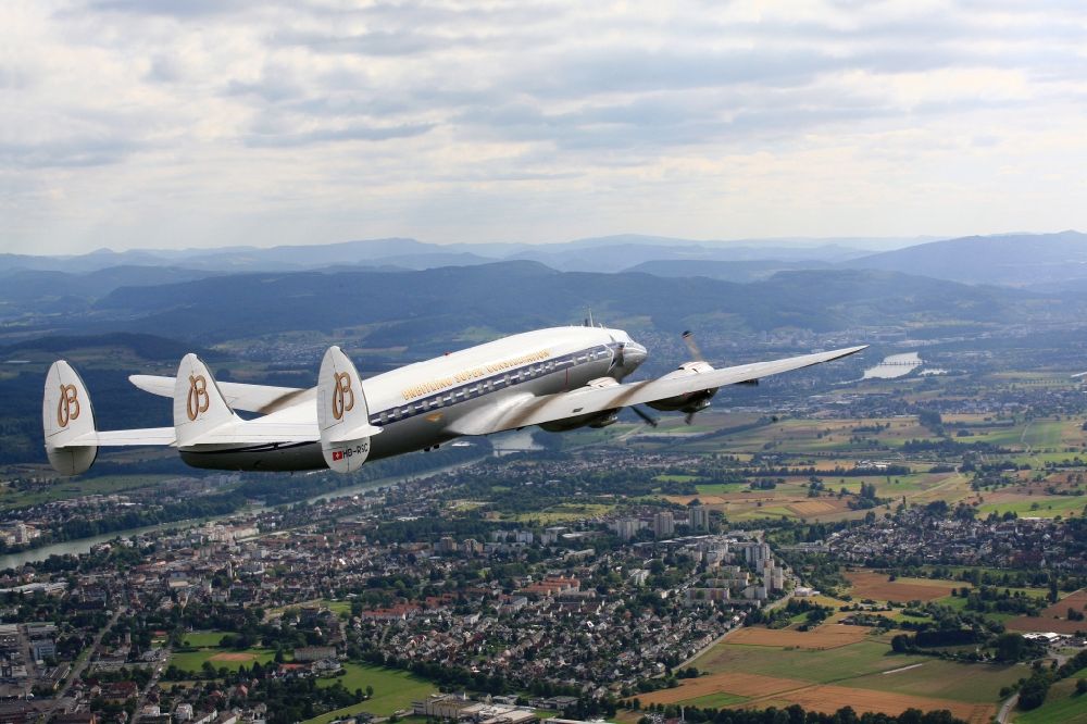 Rheinfelden (Baden) from the bird's eye view: Lockheed L1049 Super Constellation Aircraft in flight in the airspace over Rheinfelden in the state Baden-wurttemberg. The Breitling Super Constellation is one of yet only two flying aircraft in the world of this legendary airliner and belongs to the Super Constellation Flyers Association at the Euroairport in Basle