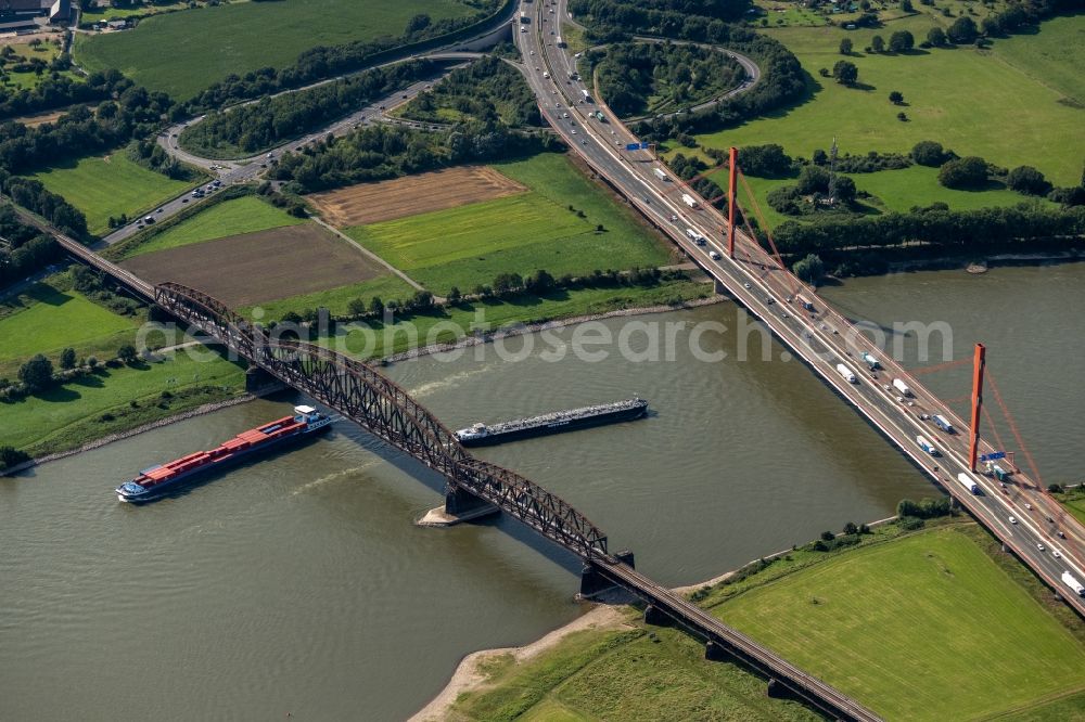 Duisburg from the bird's eye view: River - bridge construction - A42 highway bridge and railway bridge over the Rhine in the district Baerl in Duisburg at Ruhrgebiet in North Rhine-Westphalia
