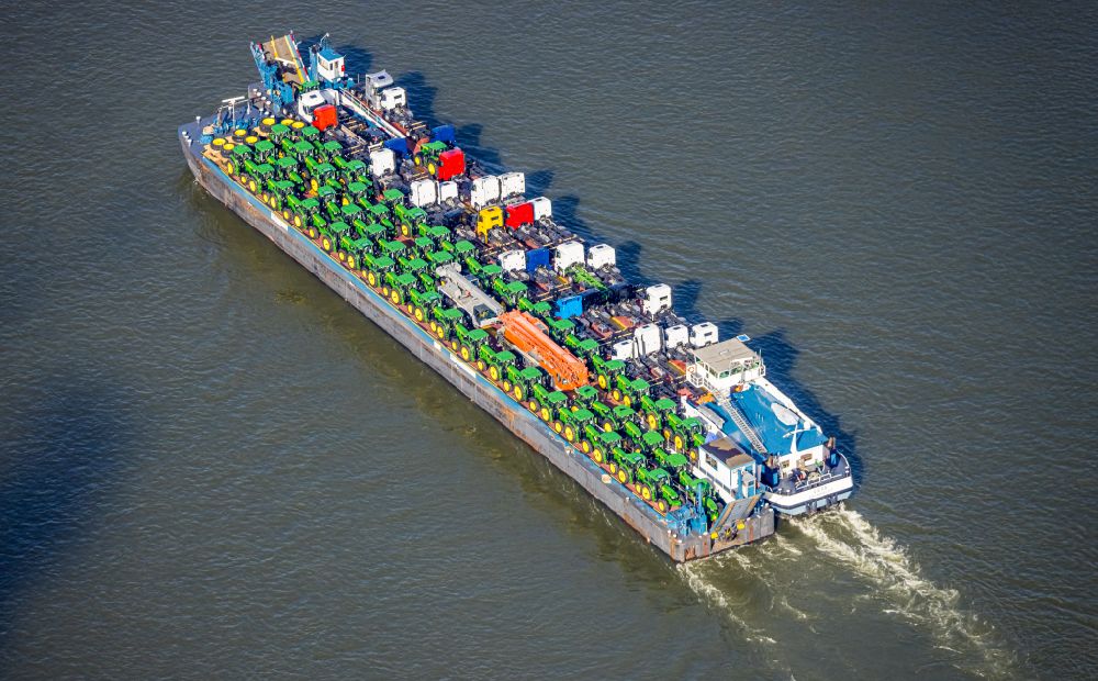 Duisburg from the bird's eye view: Cargo ship loaded with tractors and trucks in inland waterways in driving on the waterway of the river of the Rhine river in the district Baerl in Duisburg at Ruhrgebiet in the state North Rhine-Westphalia, Germany