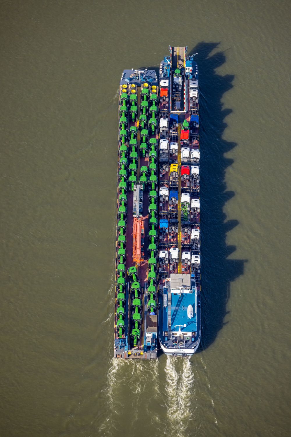 Aerial image Duisburg - Cargo ship loaded with tractors and trucks in inland waterways in driving on the waterway of the river of the Rhine river in the district Baerl in Duisburg at Ruhrgebiet in the state North Rhine-Westphalia, Germany