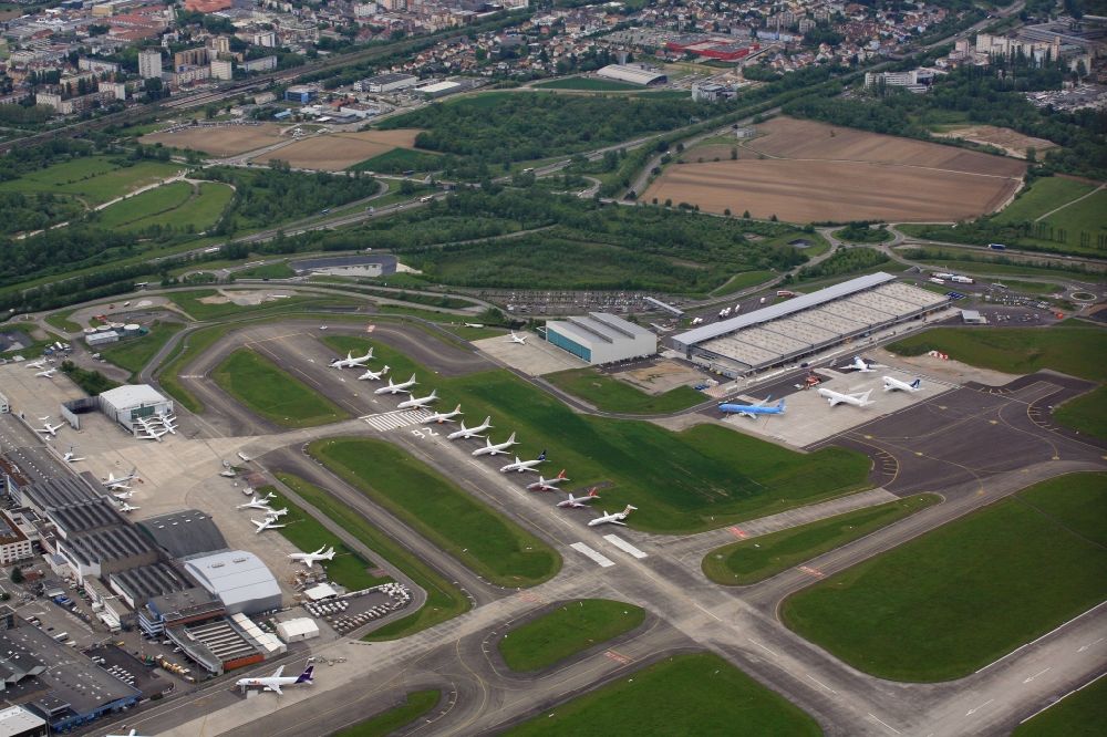 Saint-Louis from the bird's eye view: Runway with Hangars, Taxiways, tarmac and terminals on the grounds of the airport Euroairport in Saint-Louis in Alsace-Champagne-Ardenne-Lorraine, France. Many airliners are parked on the runway RWY 26