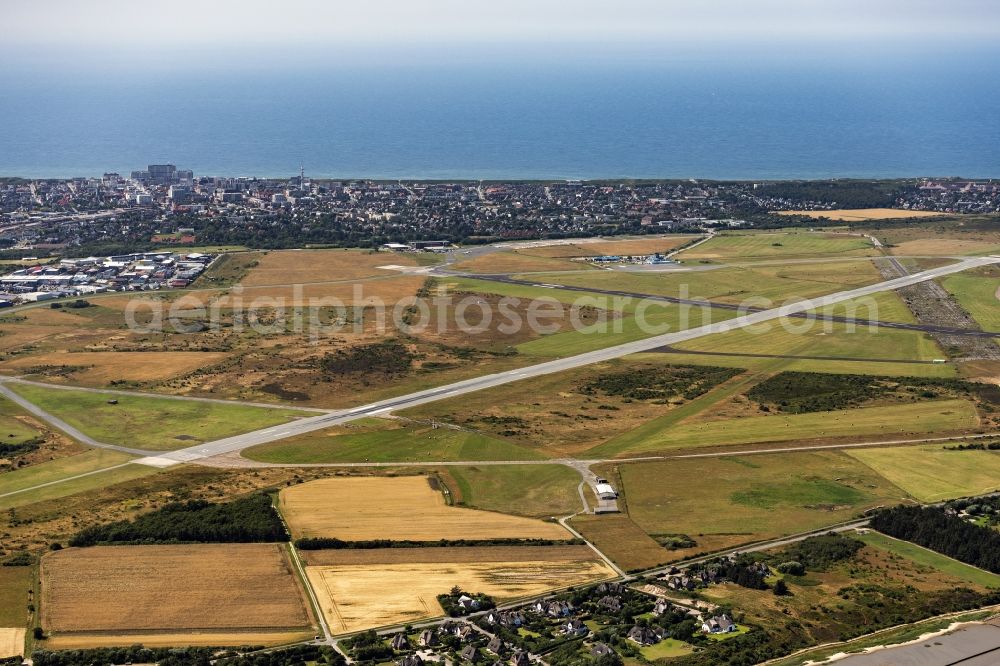 Sylt from the bird's eye view: Runway with hangar taxiways and terminals on the grounds of the airport Sylt on Sylt with the town center of Westerland in the state Schleswig-Holstein