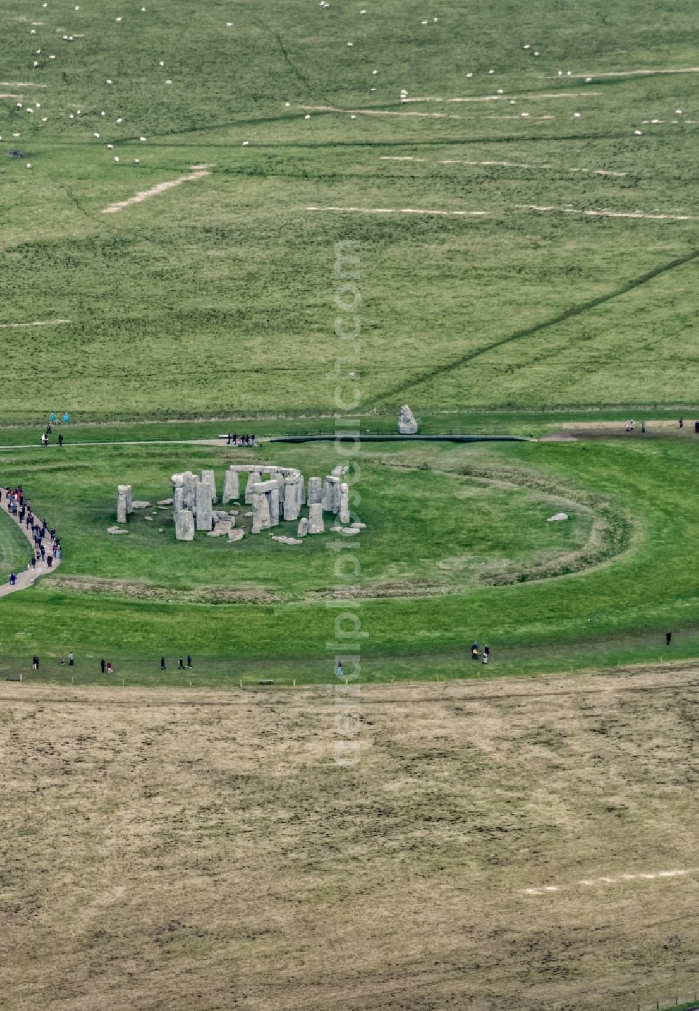 Aerial image Amesbury - Attraction and tourist attraction of the historical monument Stonehenge on a green grass field in Amesbury in UK United Kingdom. The building consists of a circular grave facility, which is surrounded by a Megalithstruktur formed of several concentric stone circles. It's origins are not known although it is thought to have evolved over a period of 1500 years. It was added to UNESCO's list of World Heritage Sites and is a legally protected Scheduled Ancient Monument