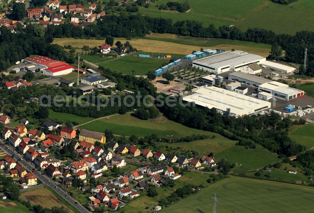 Krölpa from above - At the southeastern edge of Kroelpa in Thuringia, several companies are established in a commercial area. On the path of specializing in prefabricated building has its seat in modular construction Cadolto Thuringia. In the production halls with the red roof FMS AG manufactures packaging and presentation displays. In the context of the New Road are a variety of single-family homes