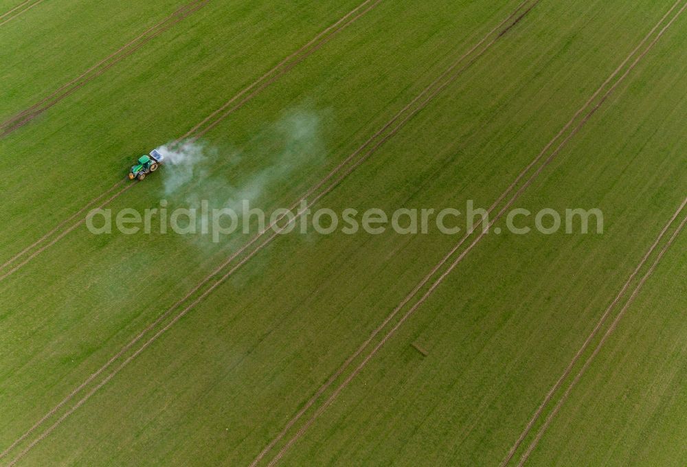 Gammelin from the bird's eye view: Spraying of lime as fertilizer with tractor and special attachment on agricultural fields in Gammelin in the state Mecklenburg - Western Pomerania, Germany