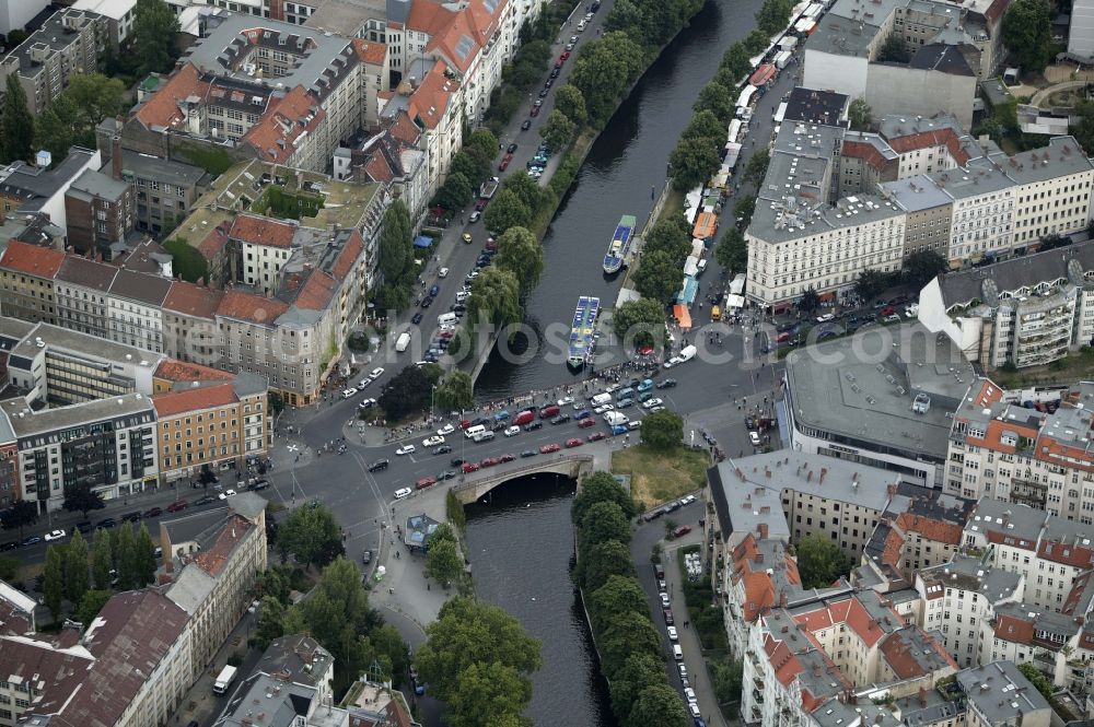 Berlin from above - The Kottbusser bridge crosses in the Kreuzberg district of Berlin in Germany Berlin Landwehr Canal. The canal is a popular tourist destination. Every day here excursion boats go. The multi-family homes at the Paul-Linke-Ufer and Maybachufer are sought after residential addresses. On the ground floor there are plenty of pubs, cafes and restaurants. Several times a week at the Maybachufer instead of selling markets. A special attraction is the Turkish market. Here Turkish specialties and products of Turkish craftsmen and artists are offered. In the large building corner Kottbusser Damm - Planufer fitness center McFit has a branch