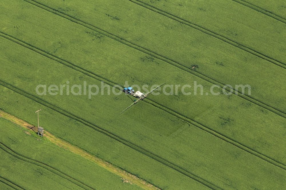 Aerial image Sömmerda - In a field at Soemmerda in Thuringia is a tractor with a trailer syringe in use. With such a trailer sprayer farmers can distribute pesticides or liquid fertilizers evenly on agricultural land. This is easily seen by the regular spacing of the lanes