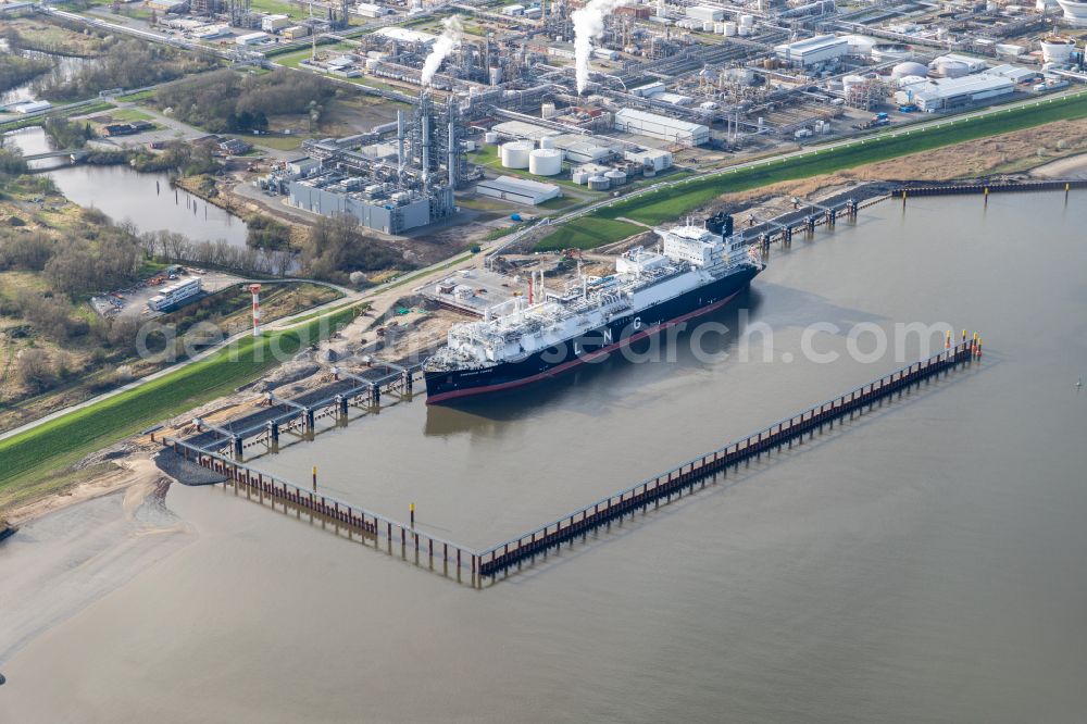 Aerial photograph Stade - Water bridge with pipeline systems of the LNG natural gas and liquid gas terminal and unloading quay with the special ship Energos Force (formerly Transgas Force) docking on the banks of the Elbe in the district of Buetzfleth in Stade in the state Lower Saxony, Germany