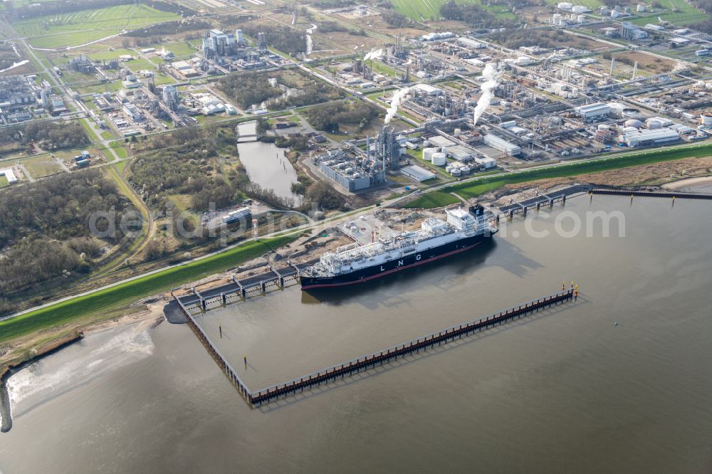 Stade from above - Water bridge with pipeline systems of the LNG natural gas and liquid gas terminal and unloading quay with the special ship Energos Force (formerly Transgas Force) docking on the banks of the Elbe in the district of Buetzfleth in Stade in the state Lower Saxony, Germany