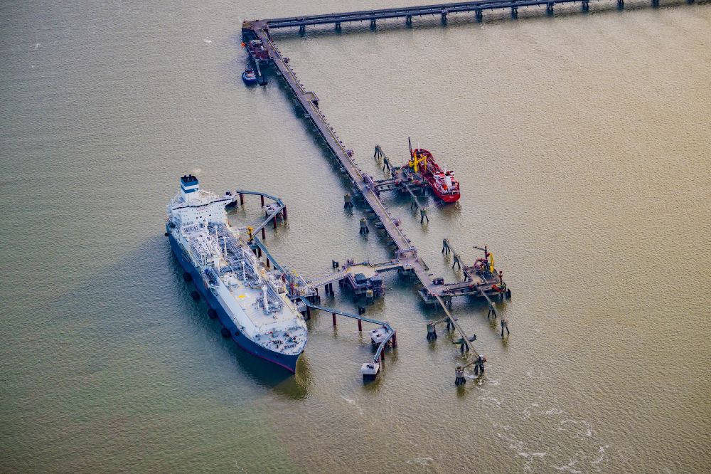Hooksiel from the bird's eye view: Water bridge with line systems of the LNG natural gas and liquid gas terminal and unloading dock when unloading the Hoeegh Esperanza an LNG storage and evaporation ship in Hooksiel in the state Lower Saxony, Germany